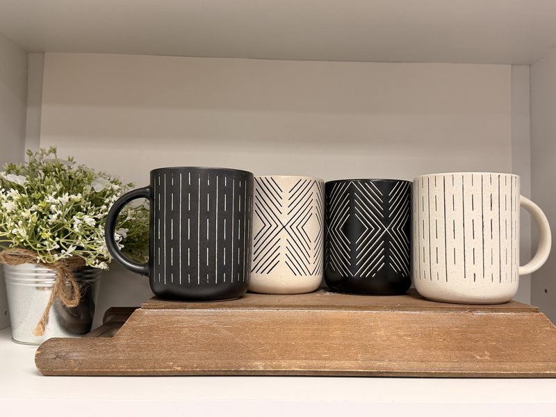 Hand-thrown mugs lined up on a wood board at Soco Chic Boutique