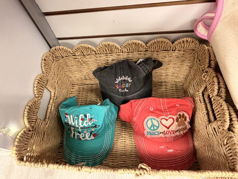 A woven basket of embroidered ball caps on a Soco Chic cubby shelf